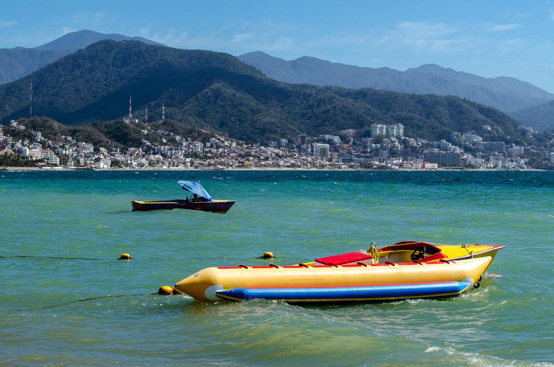 Small boats resting in a Puerto Vallarta bay with green mountains behind