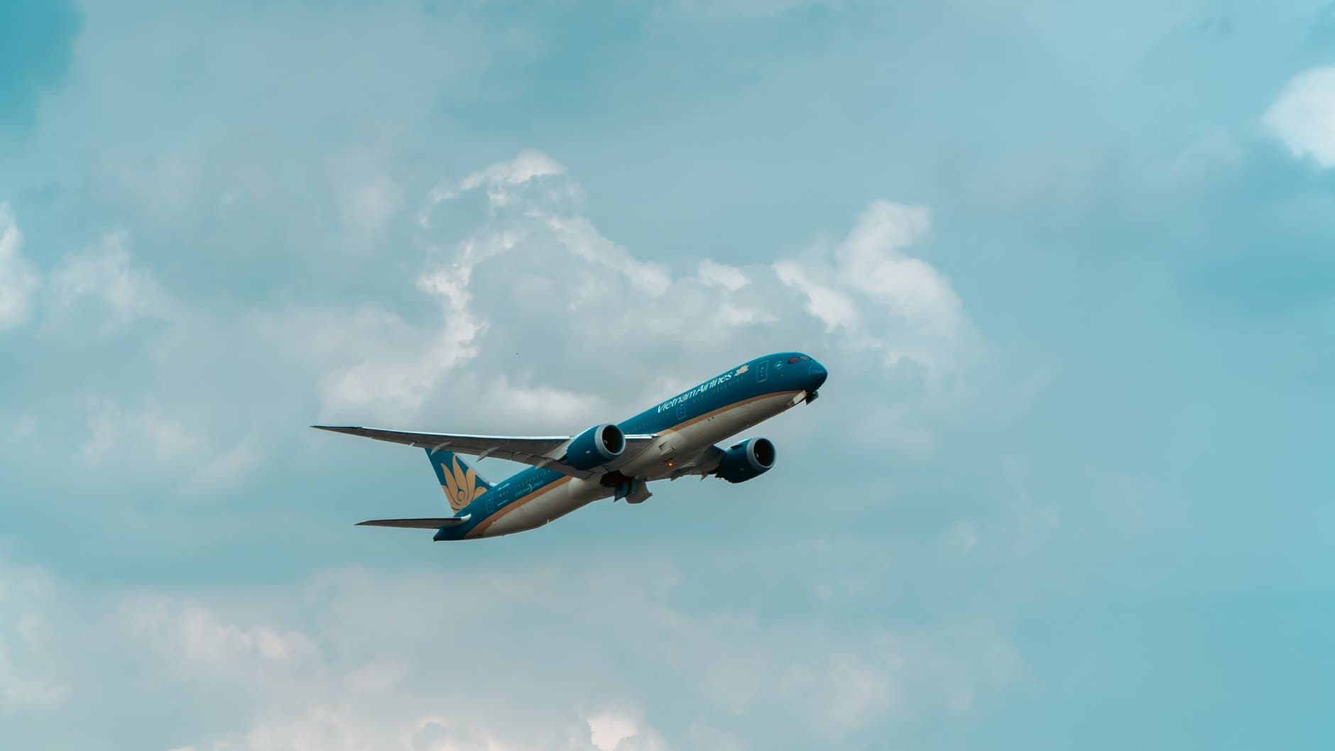 A commercial airplane flying through a blue, cloud-streaked sky