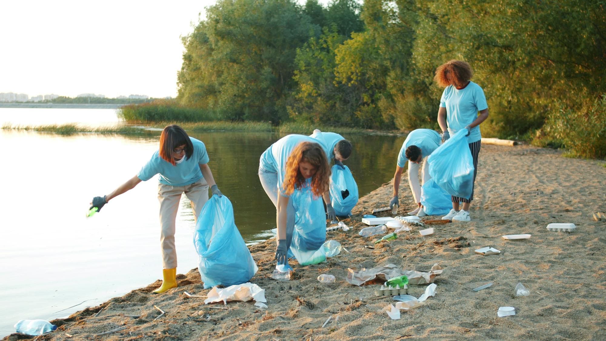 Volunteers cleaning a beach shoreline at sunset